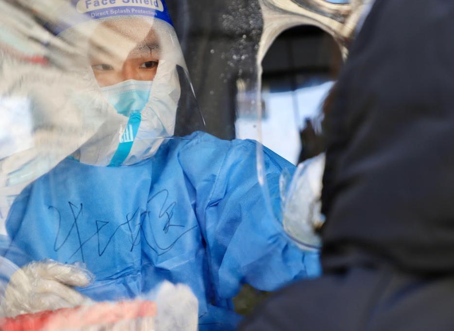 A medical worker takes a swab sample from a citizen for nucleic acid test at a testing site in Suifenhe